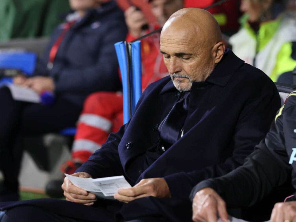 Luciano Spalletti legge un foglio in panchina